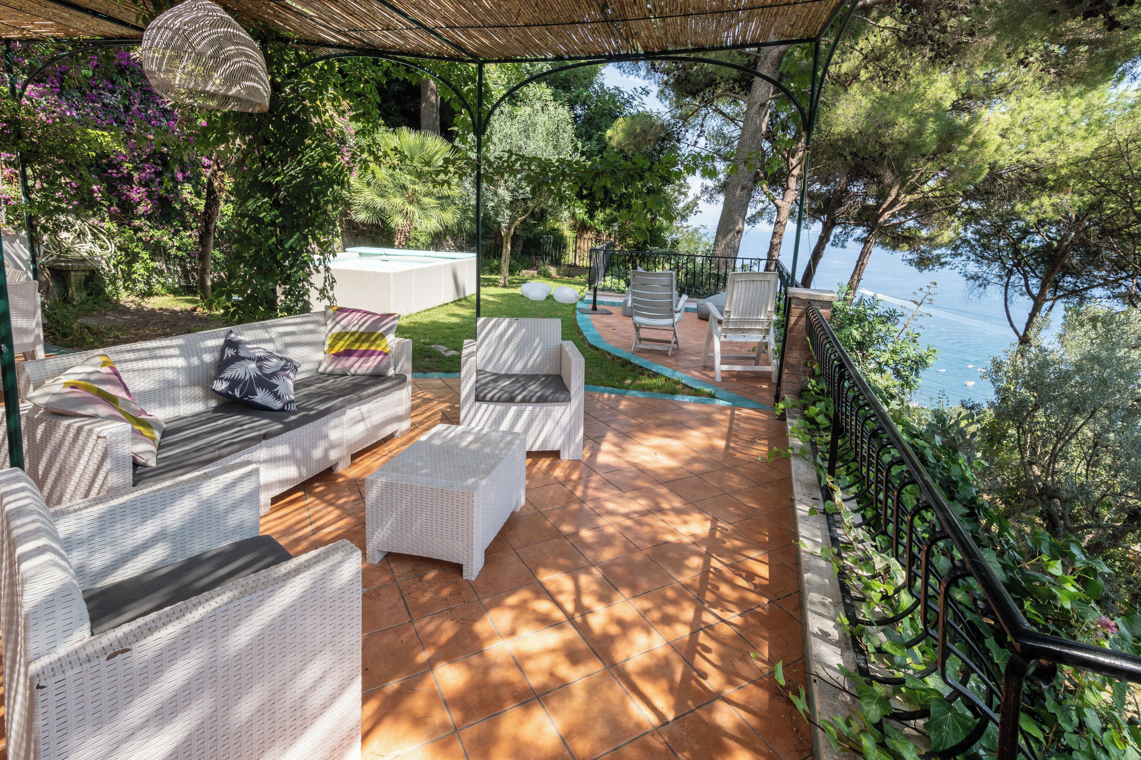 Un'area salotto esterna riparata, con mobili in vimini, un tavolo da biliardo e vista sul mare.
