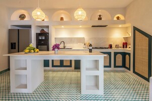 A modern kitchen with a central island, pendant lighting, and a patterned floor.