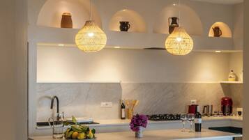 Una cucina moderna con illuminazione a sospensione, un piano di lavoro in marmo e un forno integrato.
