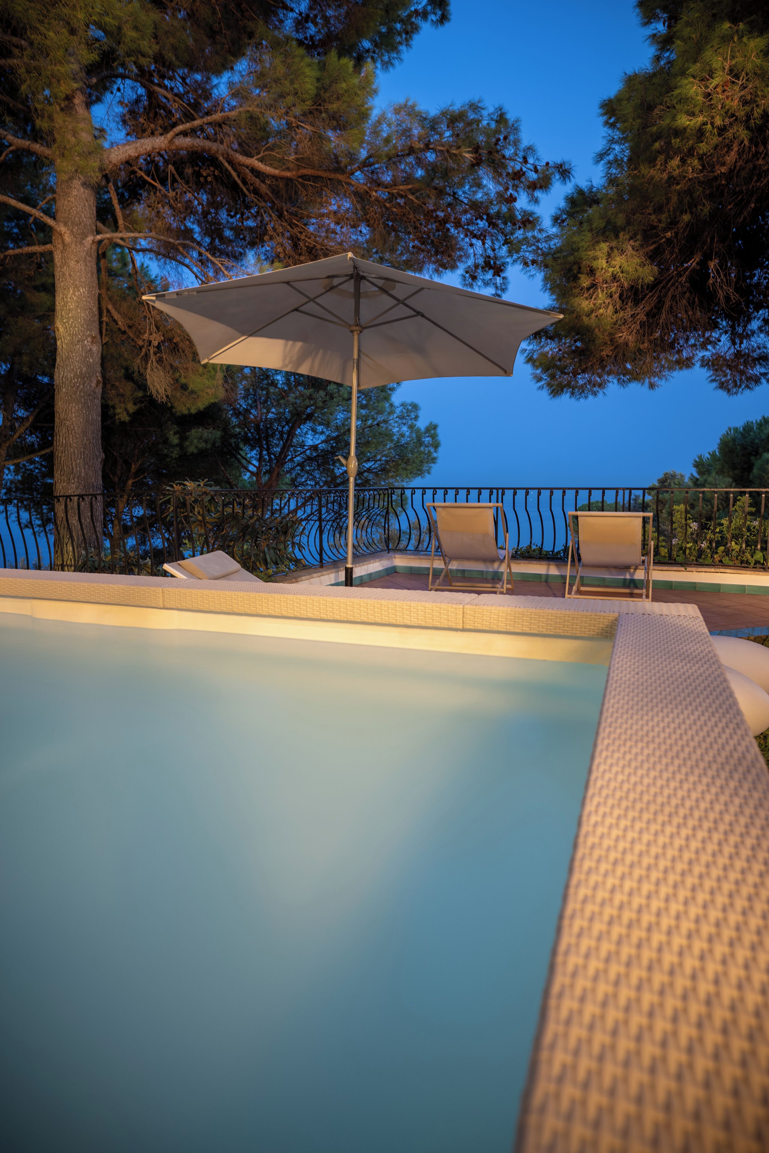 Une piscine avec des chaises longues et un parasol.