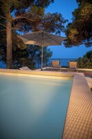Una piscina con sillas de descanso y una sombrilla.