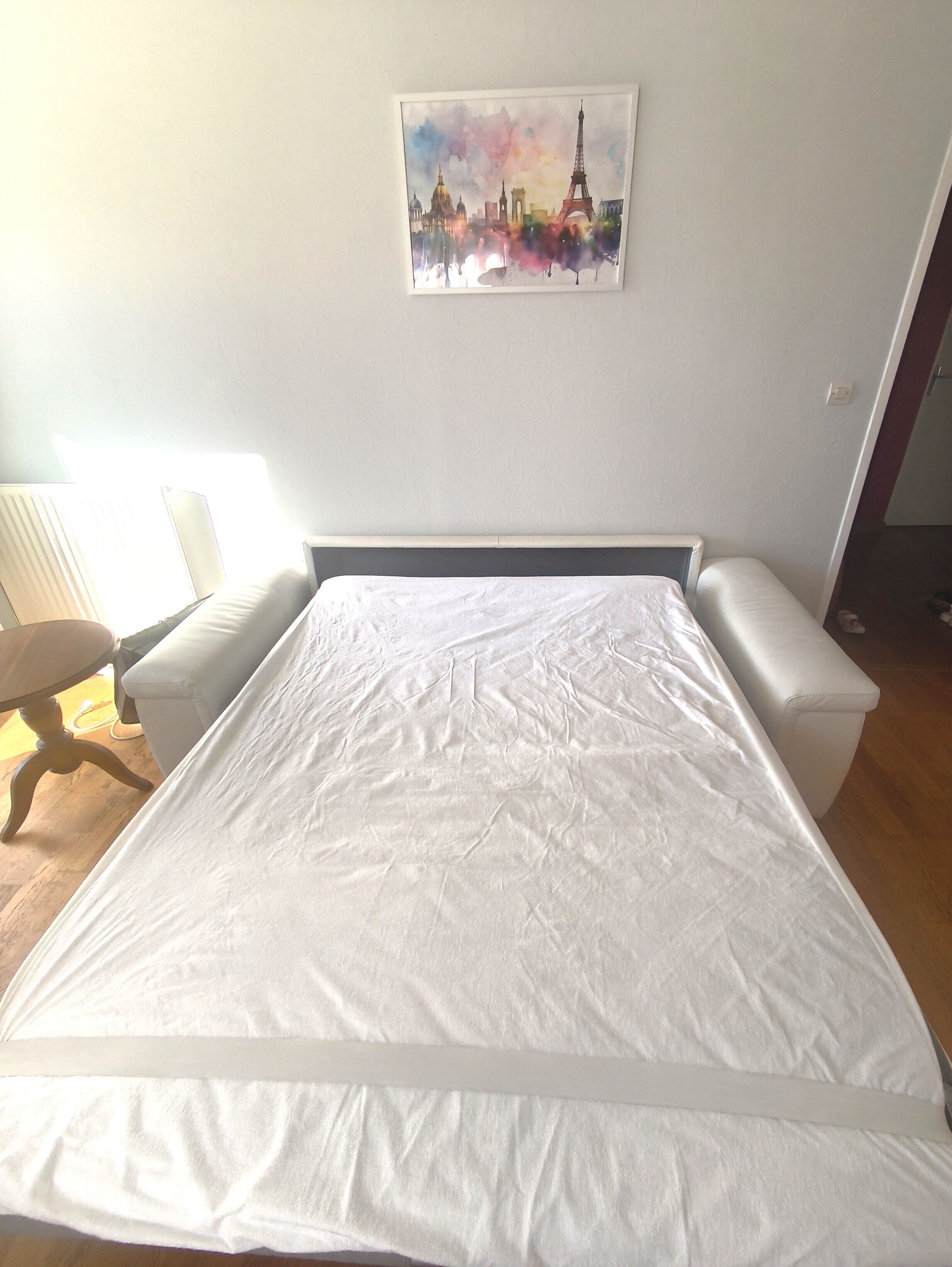 Un dormitorio con una cama grande, una silla, un escritorio y un cuadro colgado en la pared.