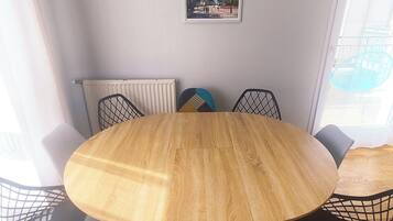 Une table ronde en bois, entourée de six chaises, une affiche de Disneyland accrochée au mur et une fenêtre avec des rideaux.