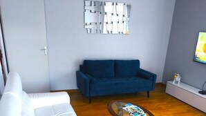 A living room with a white sofa, a blue sofa, a coffee table, and a wall-mounted TV. - Comfortable apartment—5-minute walk to the RER An at Busy-Saint-Georges—8 minutes to Disney. (Bussy-Saint-Georges)