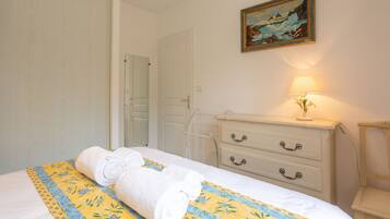 Ein Hotelzimmer mit Bett, Kommode, Lampe und einem Bild an der Wand.