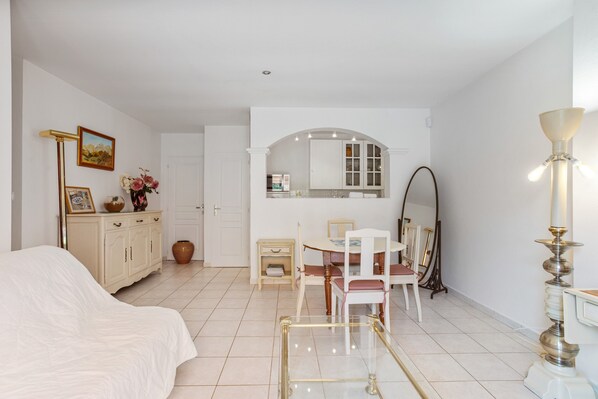 A bedroom with a bed, a bedside table, a dresser, a mirror, and a lamp.
