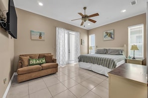 A bedroom with a bed, a couch, a ceiling fan, and a window with blinds. - Isla Bella - 2BR Steps from the Beach with Pool (South Padre Island)