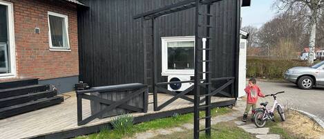 A black building with a wooden deck, a window, and a white door.