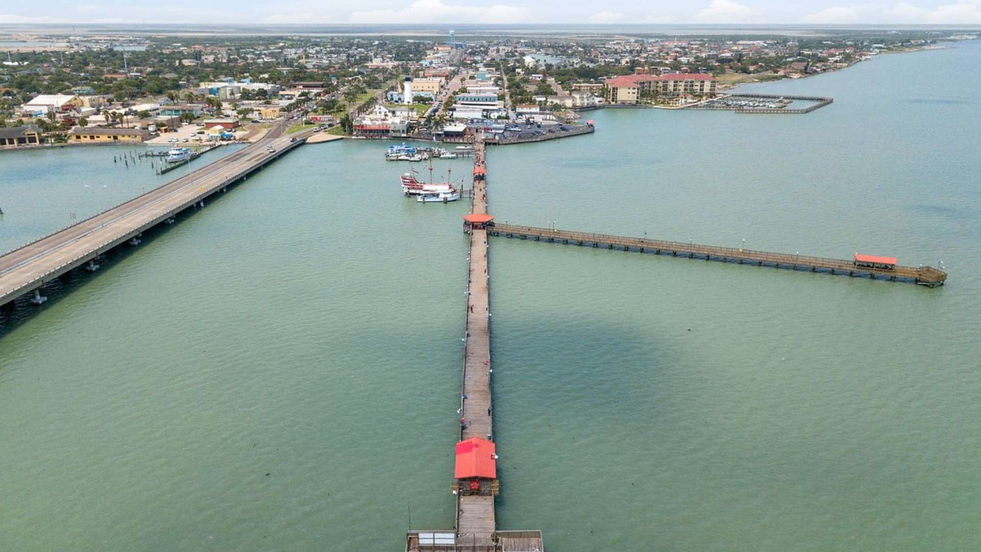 Eine lange Pier, die sich über ein Gewässer erstreckt, mit einer Skyline im Hintergrund.