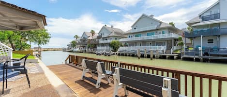 A waterfront property with a wooden deck, outdoor seating, and a view of the water.