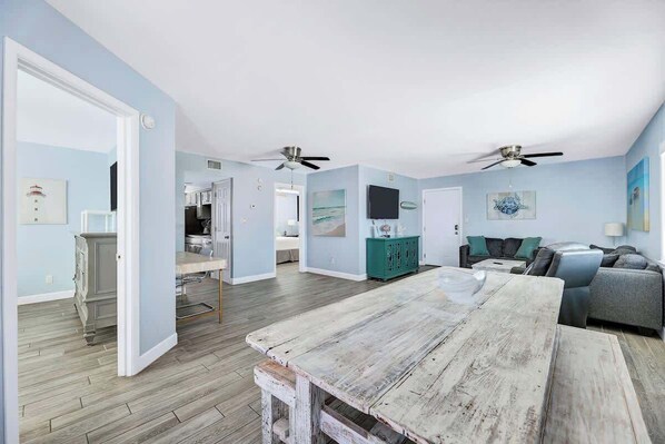 Un amplio espacio habitable con una mesa de comedor de madera, un sofá y un televisor montado en la pared.