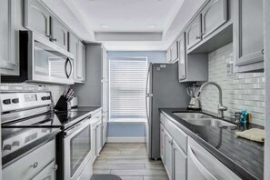 Una cocina estrecha con microondas, estufa, refrigerador y lavaplatos.