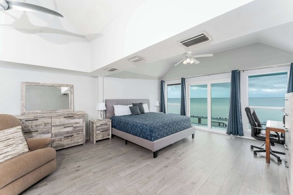 Un dormitorio con cama, tocador, silla, escritorio y un ventanal con vistas.