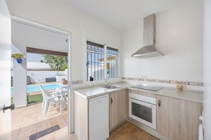 A kitchen with a dishwasher, oven, and a window with a view of a pool.