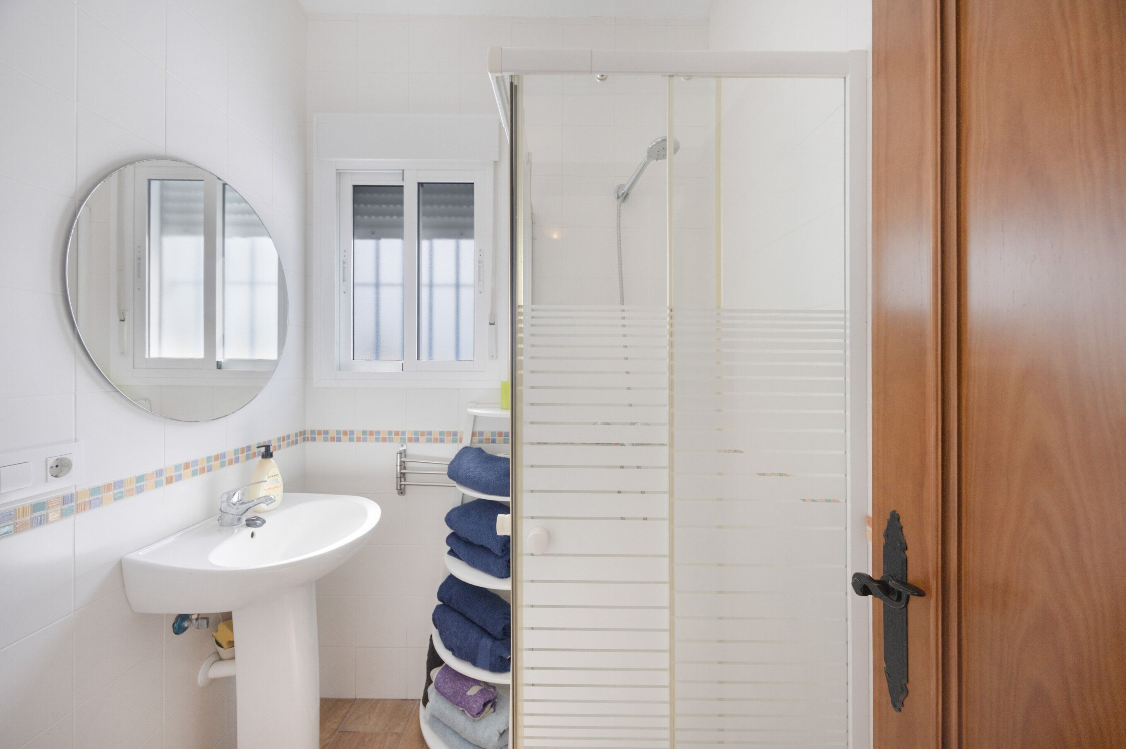 Une salle de bain équipée d’un lavabo, d’un miroir, d’un porte-serviettes et d’un espace douche.