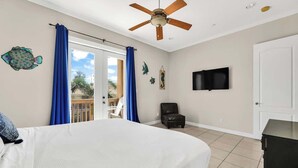 A bedroom with a bed, a ceiling fan, a TV, and a view of the outdoors. - Isla Bella - 2BR, Balcony & Pool, Beachfront Condo (South Padre Island)