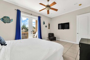Ein Schlafzimmer mit Bett, Deckenventilator, Fernseher und Blick ins Freie.