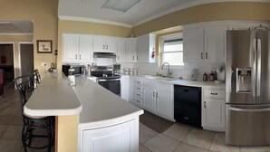 Una cocina con armarios blancos, un refrigerador de acero inoxidable y una isla central.