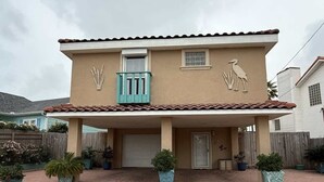 Una casa de dos pisos con un porche cubierto, una puerta principal y detalles decorativos en la pared.