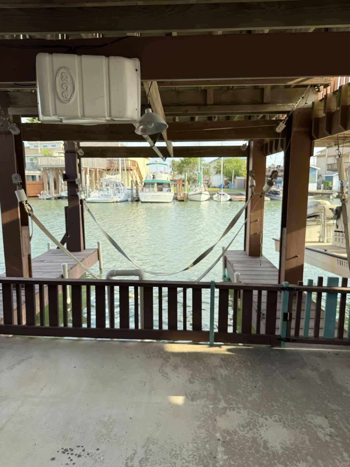 A view from a covered outdoor area with a hammock, wooden deck, and a view of boats on water.
