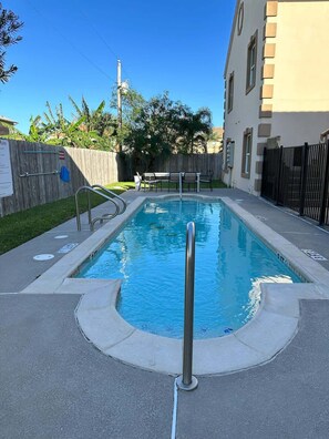Ein rechteckiger Swimmingpool mit einem Metall-Geländer im Vordergrund.