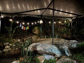 A covered outdoor area with string lights, rocks, and vegetation. - Charming 2-bedroom house in San Gerardo de Rivas perfect for relaxing (San Gerardo de Rivas)