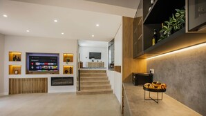 A modern living room with a flat-screen TV, wooden accents, and a staircase leading to an upper level. - California Dream Luxury Villa (Poljica)