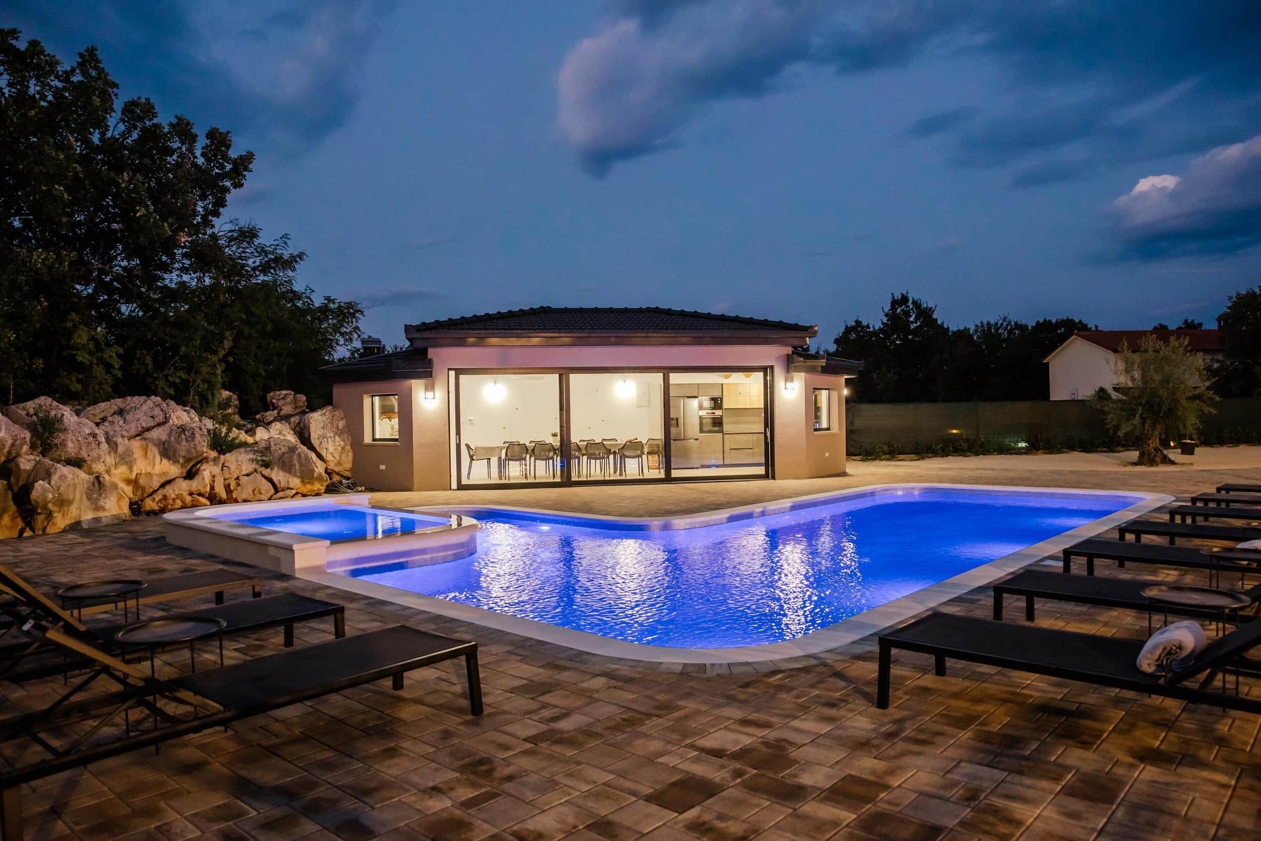 Une maison moderne dotée d’une piscine, d’un espace extérieur aménagé et d’un intérieur bien éclairé.