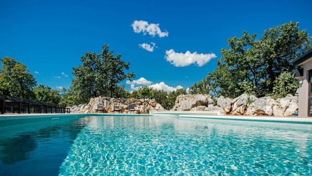 A clear blue pool with lounge chairs and a rocky backdrop. - California Dream Luxury Villa (Poljica)