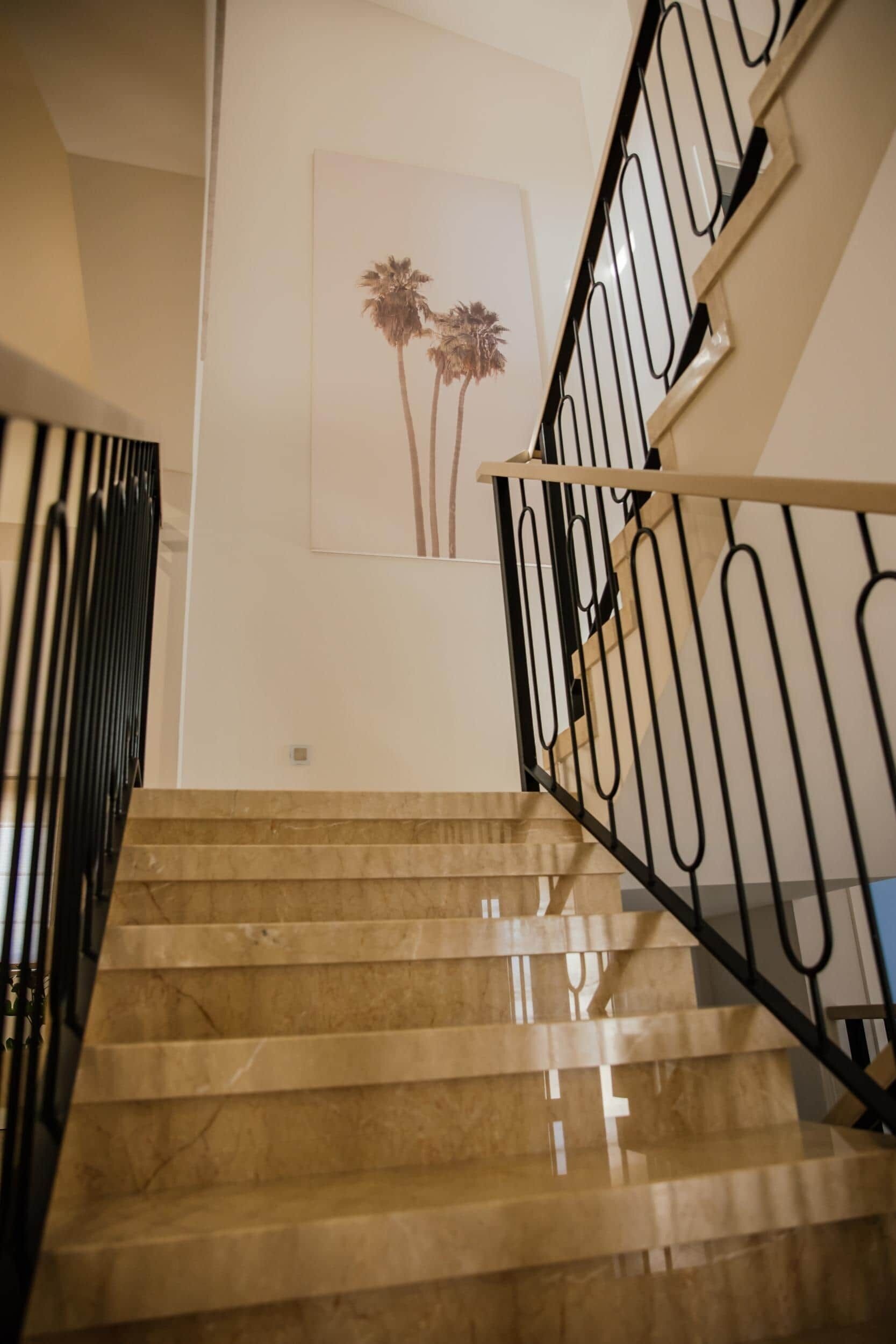 A staircase with a marble finish and black metal railings.