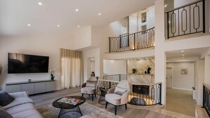 A spacious living area with a flat-screen TV, comfortable seating, a fireplace, and a balcony with a railing. - California Dream Luxury Villa (Poljica)