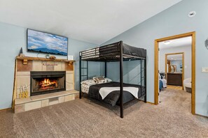 Ein Zimmer mit einem Etagenbett, einem Kamin und einem darüber montierten Fernseher.