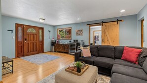 A living room with a sofa, a coffee table, a wooden door, and a sliding barn door.