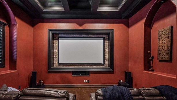 A home theater room with a large screen, leather recliners, and a brick accent wall. - 104th Mesa 1331 Paradise Found (Mesa)