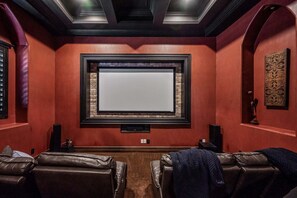 A home theater room with a large screen, leather recliners, and a brick accent wall. - 104th Mesa 1331 Paradise Found (Mesa)