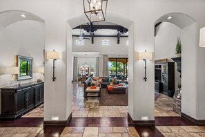 A spacious foyer with a high ceiling, a fireplace, and a seating area with a sofa and coffee table. - 104th Mesa 1331 Paradise Found (Mesa)