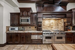 A kitchen with dark wood cabinets, a brick backsplash, a stainless steel stove, and a microwave. - 104th Mesa 1331 Paradise Found (Mesa)