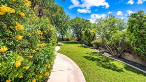 A well-maintained garden with a curved pathway, lush greenery, and flowering plants. - 104th Mesa 1331 Paradise Found (Mesa)
