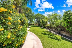 A well-maintained garden with a curved pathway, lush greenery, and flowering plants. - 104th Mesa 1331 Paradise Found (Mesa)