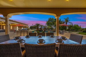 An outdoor dining area with a view of a pool and trees, featuring a table set with bowls and a grill. - 104th Mesa 1331 Paradise Found (Mesa)