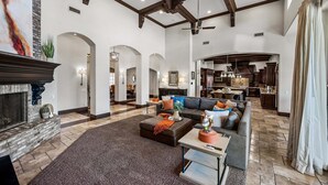 A spacious living room with a fireplace, a large sofa, a coffee table, and an archway leading to another room. - 104th Mesa 1331 Paradise Found (Mesa)