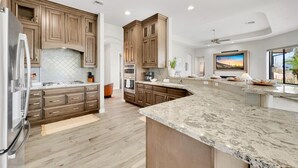 Una cocina moderna con armarios de madera, encimeras de granito y electrodomésticos de acero inoxidable.