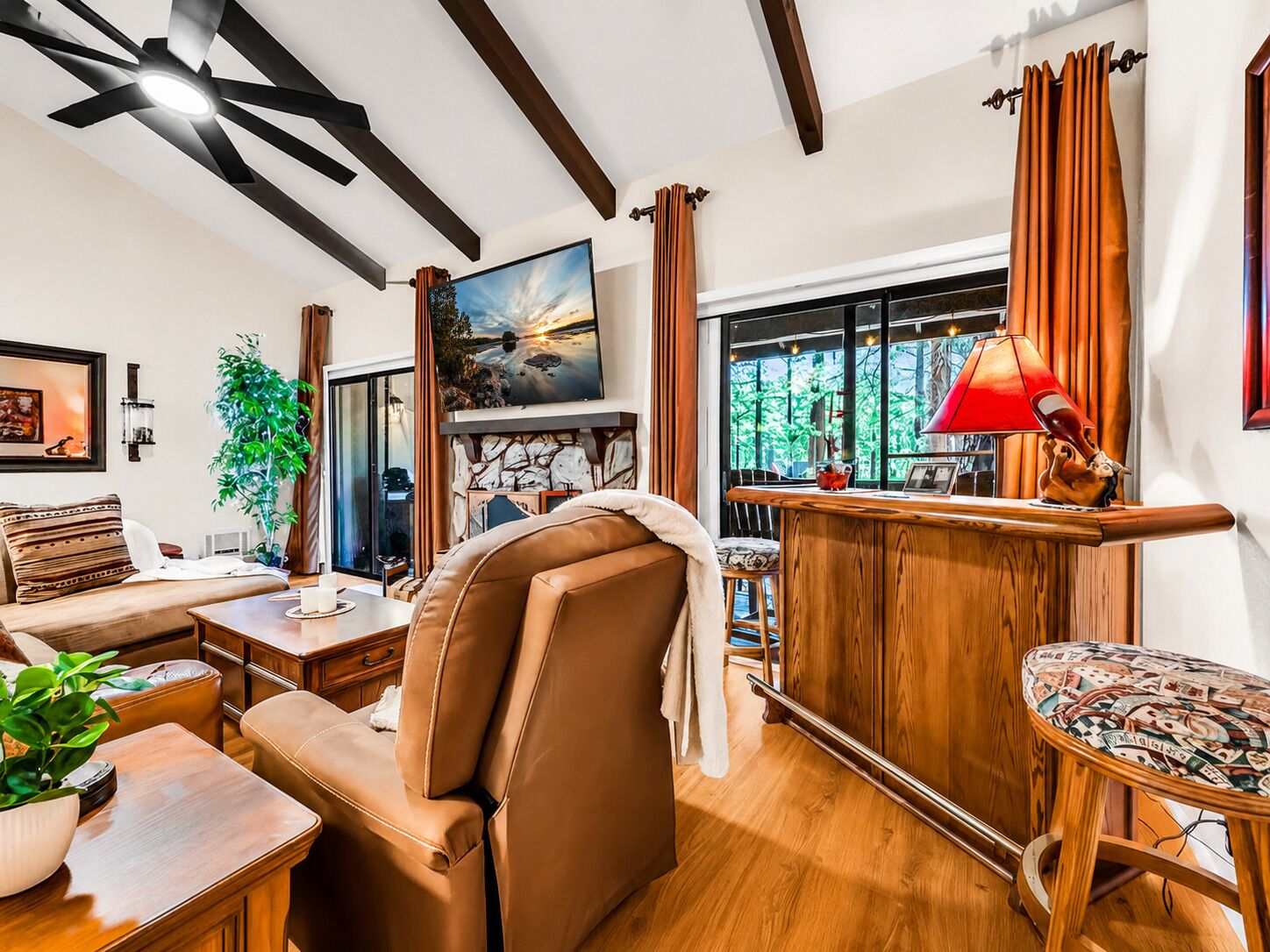 Una sala de estar moderna con chimenea, un ventanal grande y un ventilador de techo.