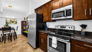 A modern kitchen with stainless steel appliances, wooden cabinets, and a dining area with a table and chairs.