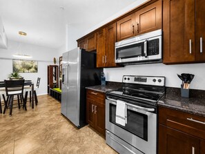 A modern kitchen with stainless steel appliances, wooden cabinets, and a dining area with a table and chairs. - Southern #1083 Mesa (Mesa)