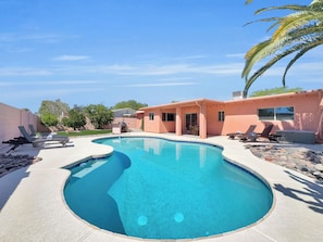 A swimming pool with a curved edge, a patio area with lounge chairs, and a small building with a door and windows. - Captain Dreyfus Phoenix (Phoenix)
