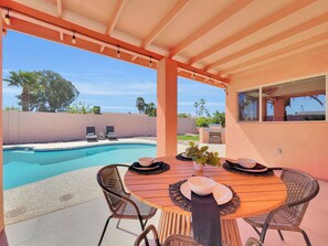 A covered outdoor area with a pool, a wooden table with chairs, and a grill in the background. - Captain Dreyfus Phoenix (Phoenix)