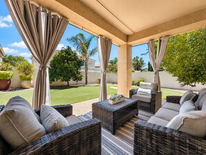 A covered patio with wicker furniture and a view of a well-maintained lawn and trees. - The Jade House Queen Creek (Queen Creek)
