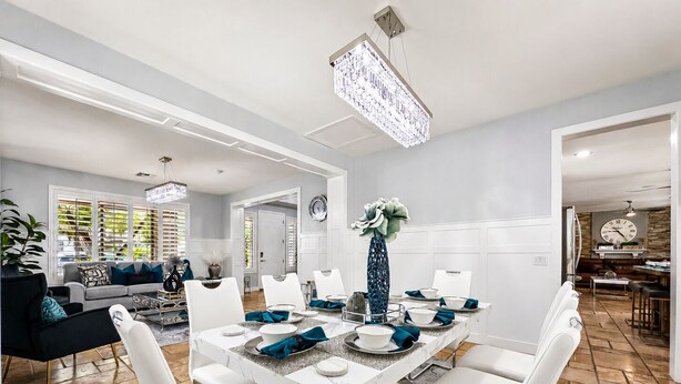 A modern dining area with a marble table, white chairs, and a chandelier. - The Jade House Queen Creek (Queen Creek)