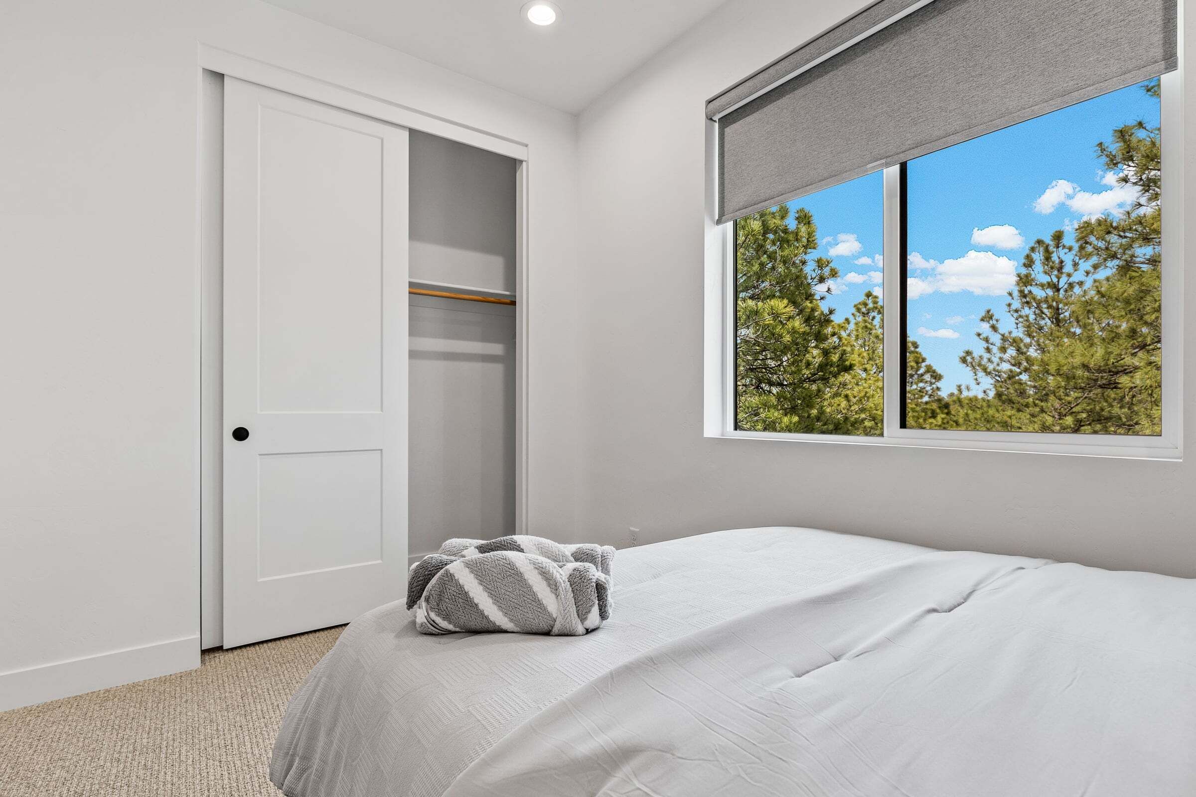 Un dormitorio con cama, armario y ventana con vistas a árboles.